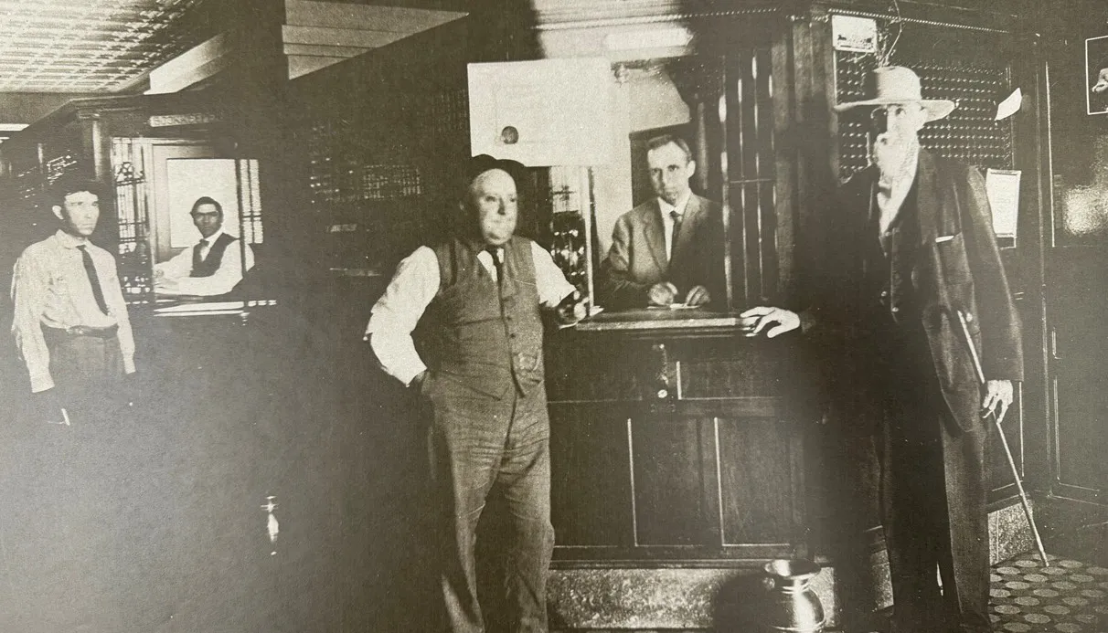 Men standing in the State National Bank lobby in 1909