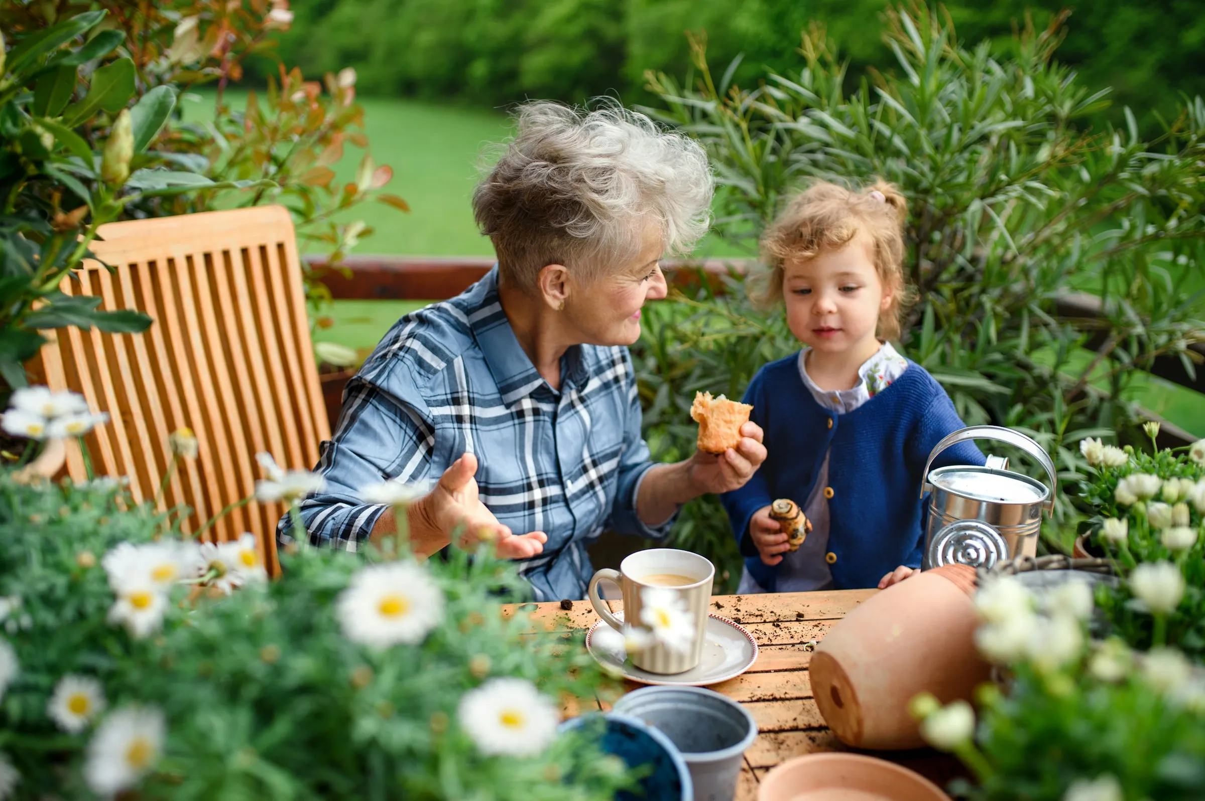 An elderly woman enjoys tea time with her small granddaughter