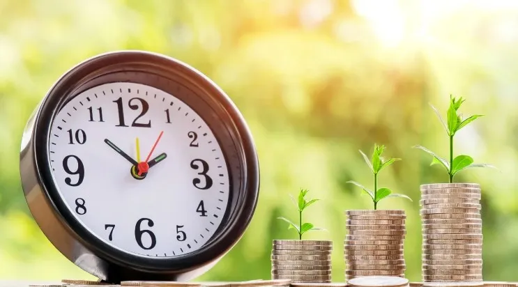 A clock with stacks of coins with plants sprouting from them